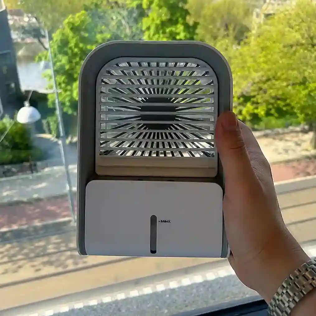 Person holding a compact Frost Cooler personal cooling device.